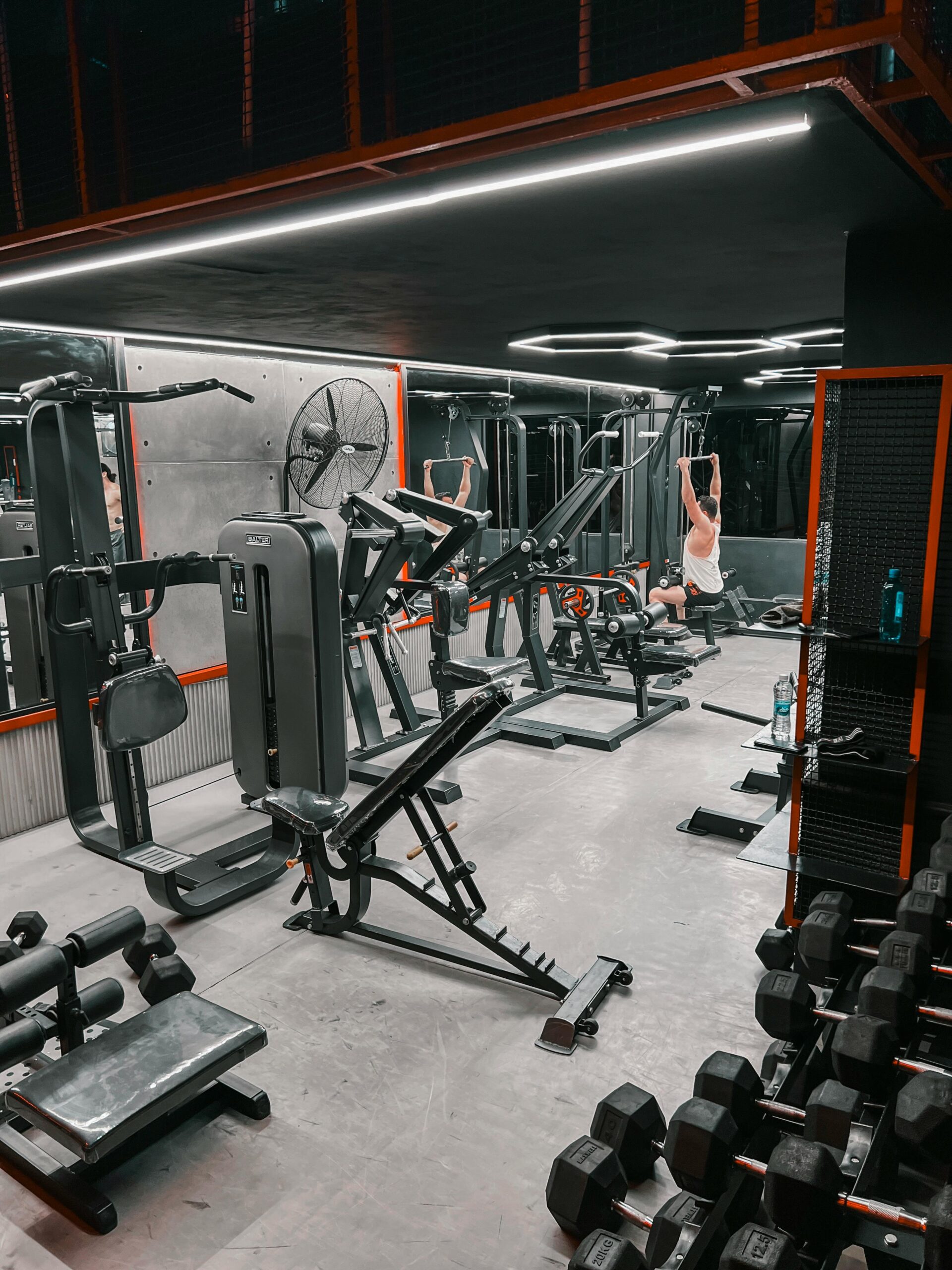 Spacious indoor gym with weight machines and a person working out.